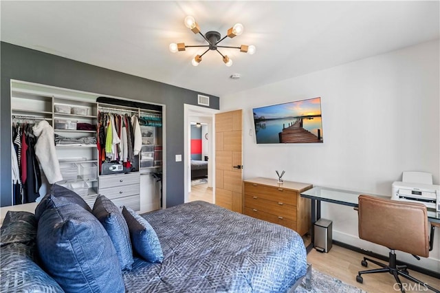 bedroom featuring an inviting chandelier, a closet, visible vents, wood finished floors, and baseboards