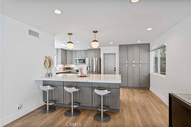 kitchen with gray cabinets, a peninsula, baseboards, and stainless steel appliances