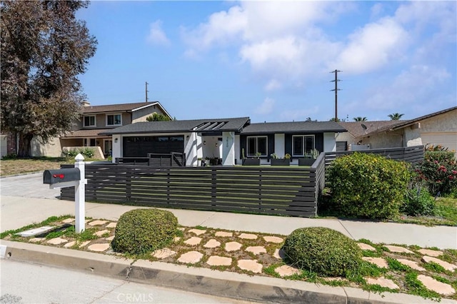 view of front of property featuring driveway, an attached garage, and a fenced front yard