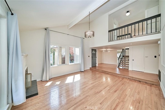 19910 Cantara St, Winnetka, CA 91306 - unfurnished living room featuring lofted ceiling with beams, light wood-style floors, a fireplace with raised hearth, a chandelier, and stairway