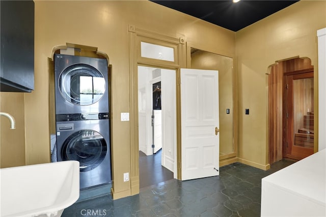 laundry area featuring baseboards, stacked washer and clothes dryer, and laundry area