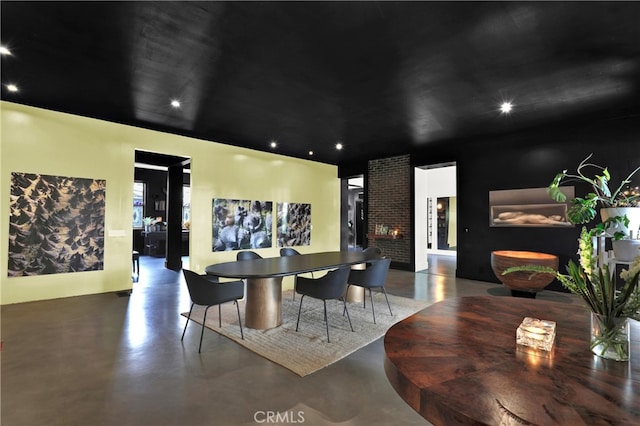 dining space featuring finished concrete floors, recessed lighting, and a fireplace