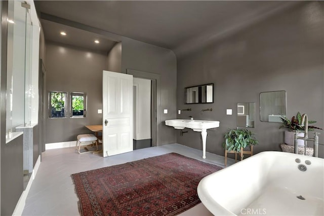bathroom with recessed lighting, a freestanding tub, and baseboards