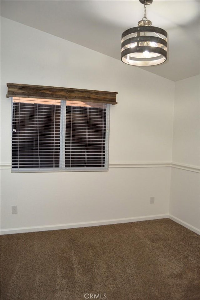 carpeted empty room featuring baseboards and an inviting chandelier