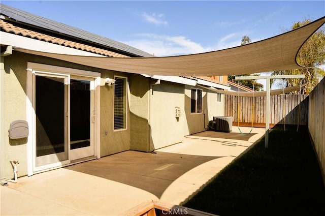 rear view of property with a patio, stucco siding, cooling unit, a fenced backyard, and solar panels