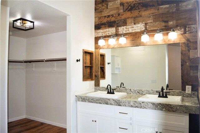 full bathroom featuring a sink, a walk in closet, double vanity, and wood finished floors