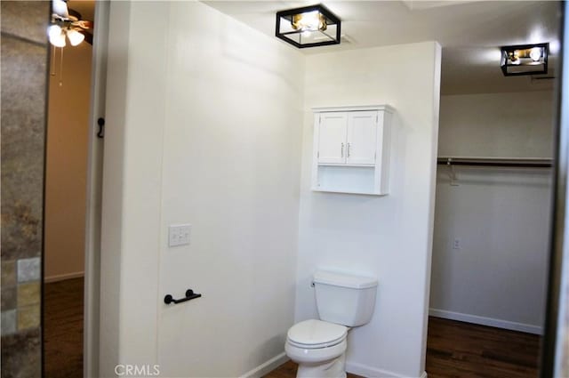 bathroom featuring toilet, wood finished floors, ceiling fan, and baseboards