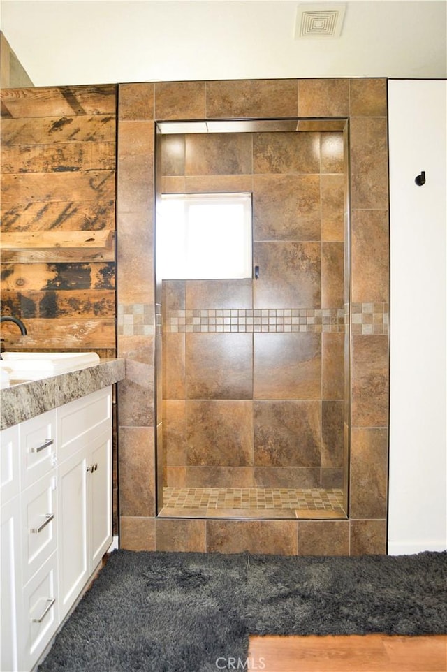 bathroom featuring a walk in shower, vanity, and visible vents