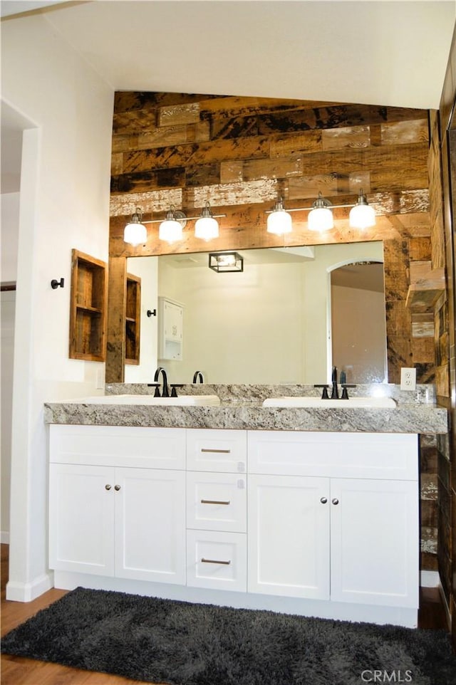 bathroom with double vanity, a sink, and wood finished floors