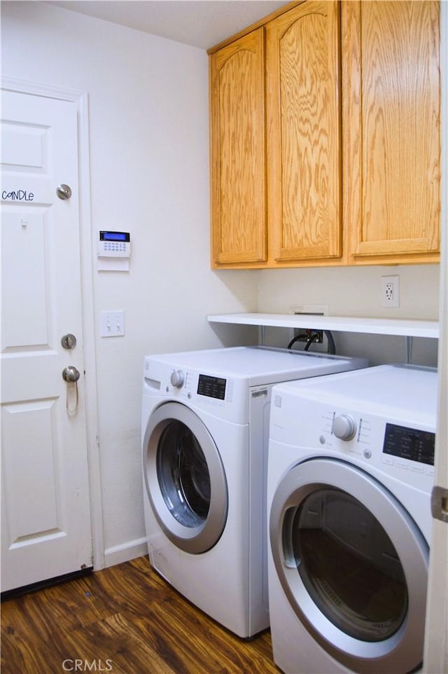 laundry room featuring dark wood-type flooring, washing machine and dryer, baseboards, and cabinet space
