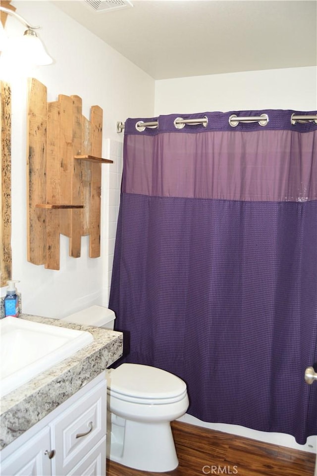 bathroom with vanity, visible vents, toilet, curtained shower, and wood finished floors