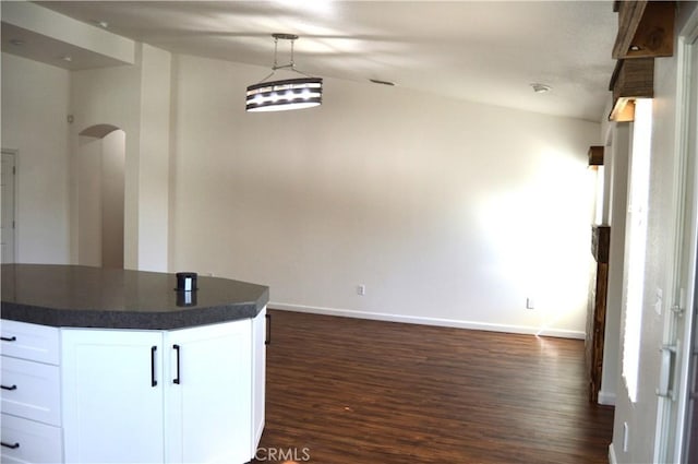 kitchen featuring pendant lighting, white cabinetry, dark wood-style flooring, dark countertops, and baseboards