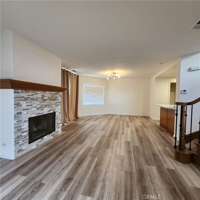 907 W Arrow, Claremont, CA 91711 - unfurnished living room with visible vents, baseboards, light wood-style flooring, and a stone fireplace