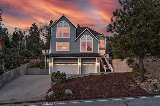 view of front of home with stairs, an attached garage, and concrete driveway