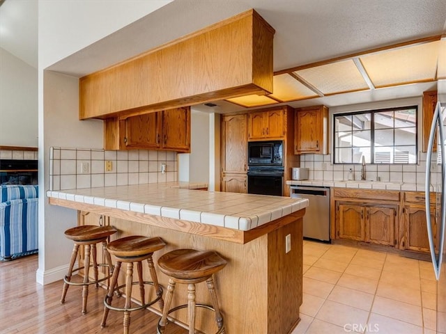 101 Searidge Ct, Pismo Beach, CA 93449 - kitchen featuring black appliances, a peninsula, decorative backsplash, and a breakfast bar