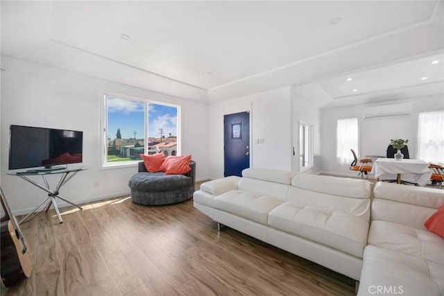 living room with wood finished floors, baseboards, recessed lighting, a wall mounted AC, and a tray ceiling