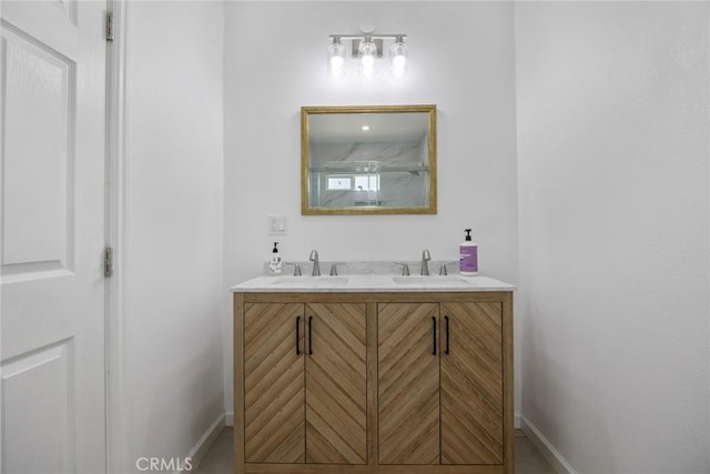full bath with baseboards, a sink, and double vanity