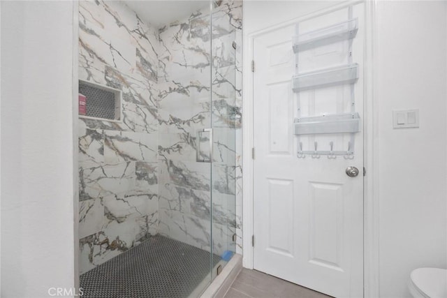 full bathroom featuring a marble finish shower and toilet