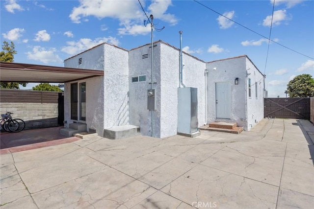 view of side of home with fence, a patio, and stucco siding