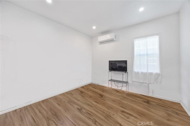 unfurnished living room with wood finished floors, recessed lighting, baseboards, and a wall mounted AC