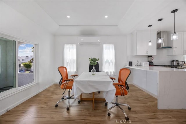 dining room with light wood-style floors, plenty of natural light, and an AC wall unit