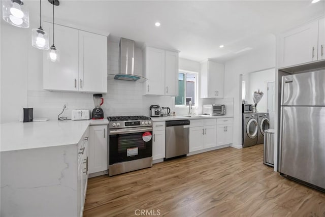 kitchen featuring decorative backsplash, stainless steel appliances, wall chimney exhaust hood, and washer and dryer