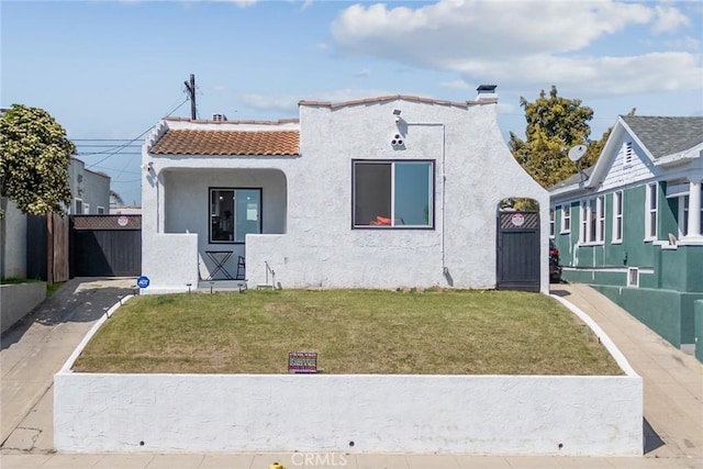 mediterranean / spanish house with a tiled roof, a gate, a front lawn, and stucco siding