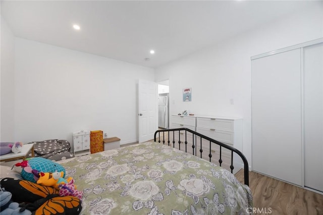 bedroom featuring freestanding refrigerator, recessed lighting, wood finished floors, and a closet
