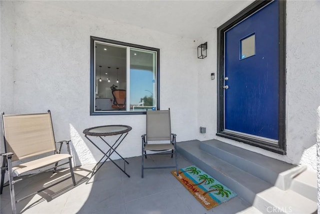 view of exterior entry with a patio and stucco siding
