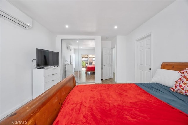 bedroom featuring recessed lighting, baseboards, a wall unit AC, and wood finished floors