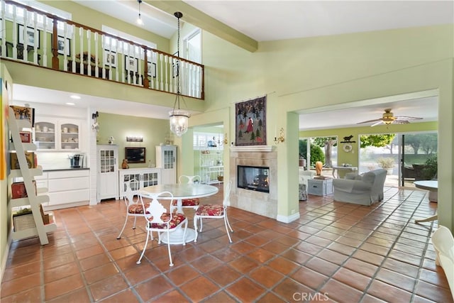 dining space with beamed ceiling, ceiling fan, high vaulted ceiling, tile patterned flooring, and a tiled fireplace