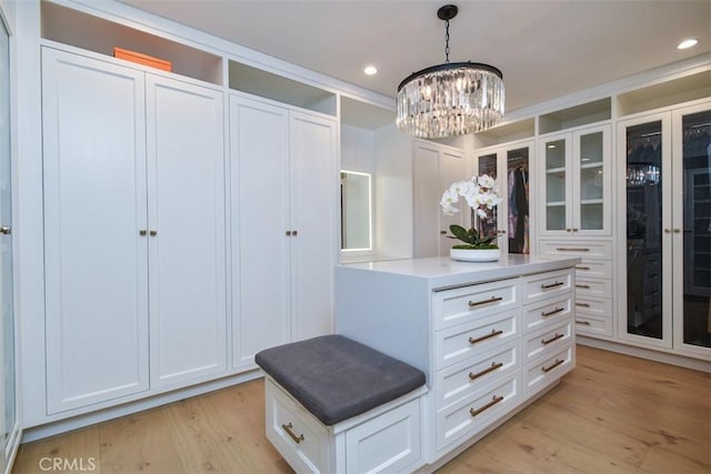 spacious closet featuring light wood-style flooring and a chandelier