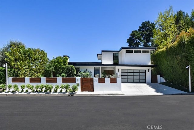 contemporary house with an attached garage, driveway, stucco siding, and a fenced front yard