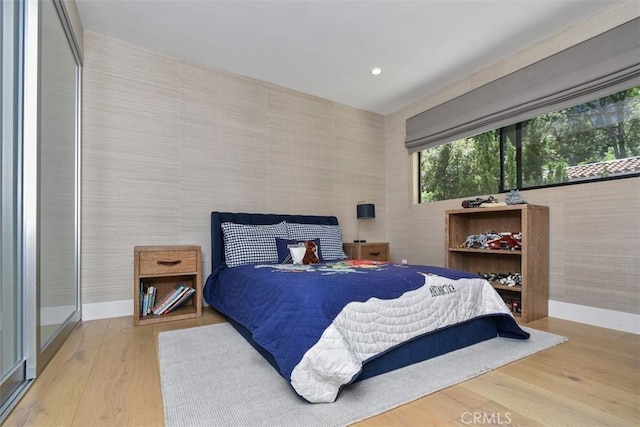 bedroom with baseboards, recessed lighting, wood finished floors, and wallpapered walls