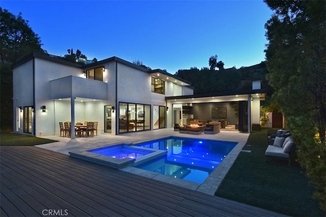 back of house featuring outdoor dining space, stucco siding, outdoor lounge area, a pool with connected hot tub, and a deck
