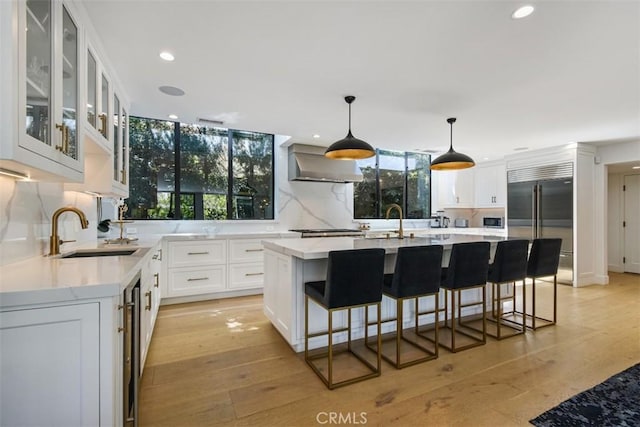 kitchen with a sink, wall chimney exhaust hood, plenty of natural light, and stainless steel appliances