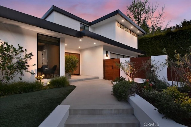 view of front of house featuring concrete driveway, stucco siding, and fence