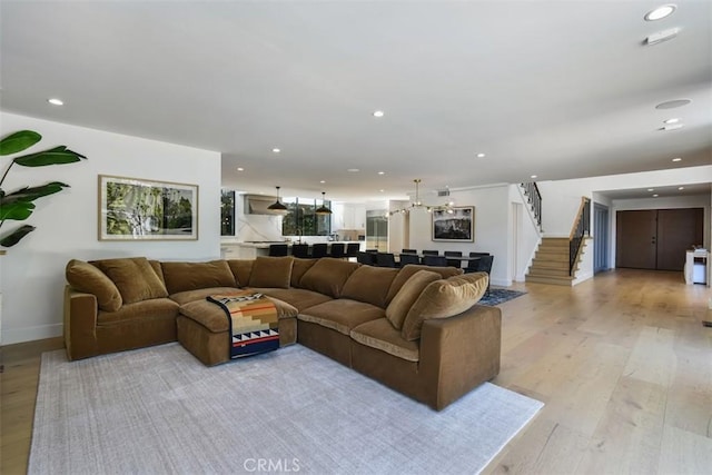 living area featuring light wood-style flooring, recessed lighting, baseboards, and stairway