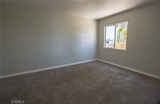 empty room with baseboards and dark carpet