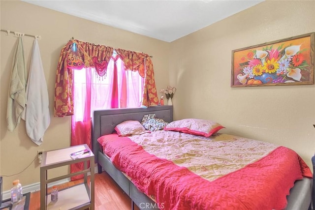 bedroom featuring baseboards and wood finished floors