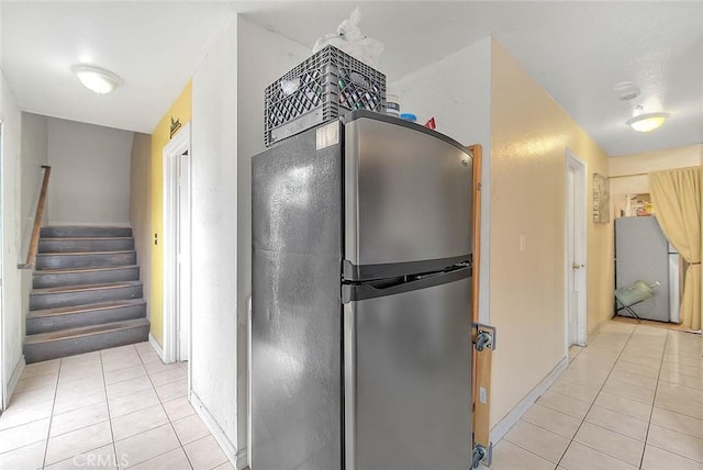kitchen with light tile patterned floors, baseboards, freestanding refrigerator, and refrigerator