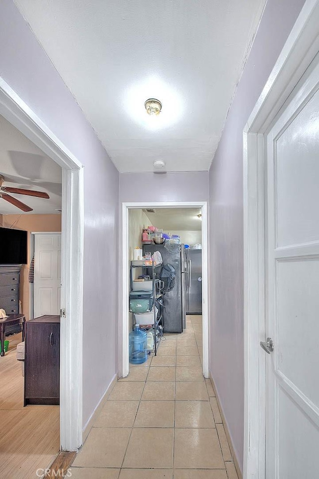 hall with light tile patterned flooring and baseboards