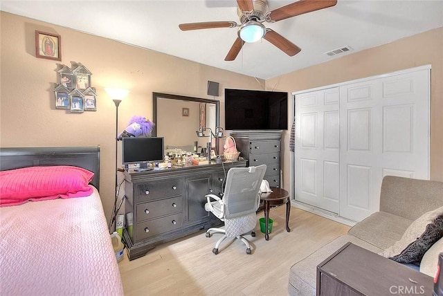 bedroom featuring ceiling fan, visible vents, a closet, and wood finished floors