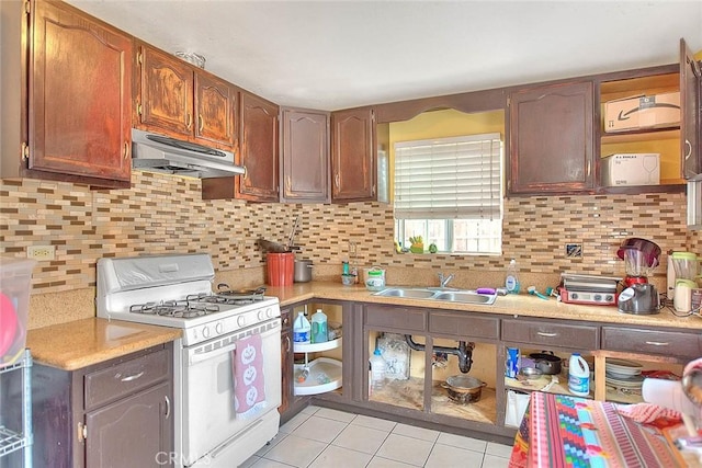 kitchen featuring light tile patterned floors, a sink, light countertops, gas range gas stove, and under cabinet range hood