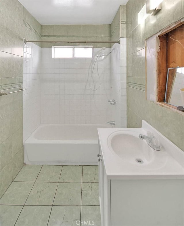 full bath with tile patterned flooring, shower / bathtub combination, vanity, and tile walls