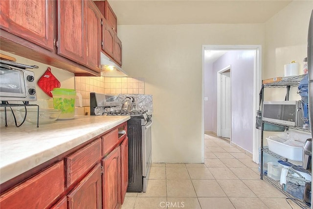 kitchen with a toaster, light tile patterned floors, light countertops, backsplash, and gas range