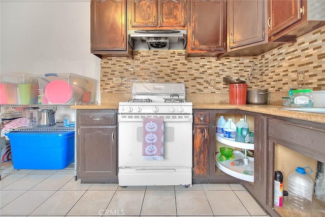 kitchen with exhaust hood, light countertops, gas range gas stove, decorative backsplash, and light tile patterned flooring