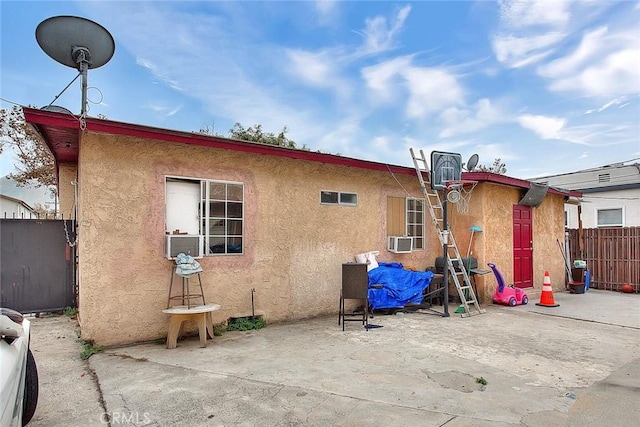 rear view of house with fence, cooling unit, a patio, and stucco siding