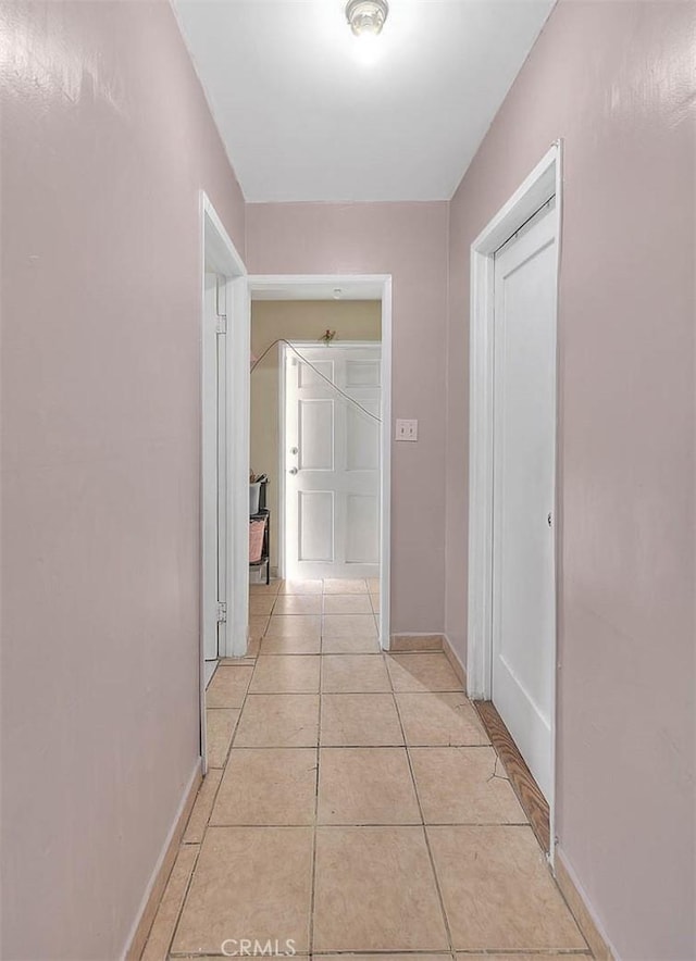 corridor featuring light tile patterned floors and baseboards