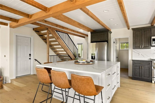 27684 St Bernard Ln, Lake Arrowhead, CA 92352 - kitchen with appliances with stainless steel finishes, a breakfast bar, beam ceiling, light wood-style floors, and a center island